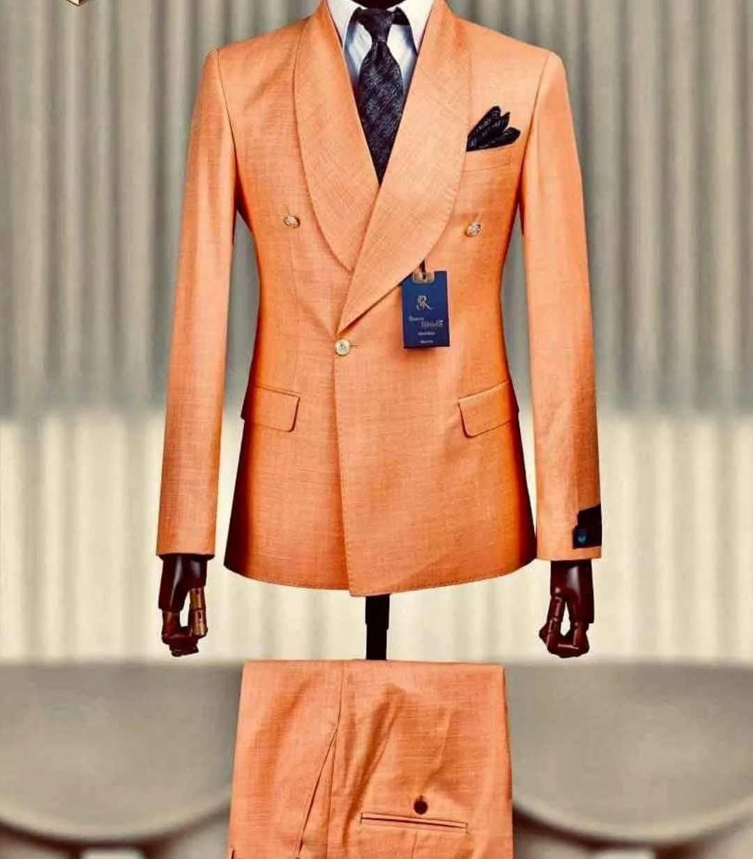 A tangerine-coloured double-breasted reception suit on a tailor's mannequin.