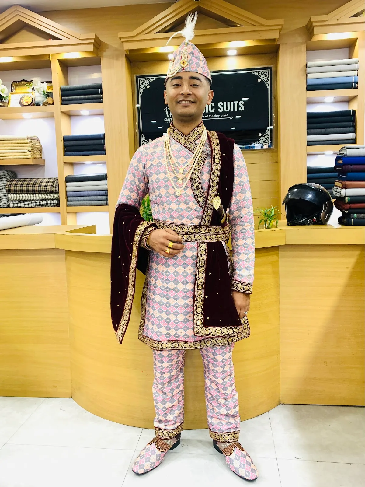 Pink-and-gold diamond-pattern sherwani with embroidered maroon shawl, tailored for a Pokhara wedding.